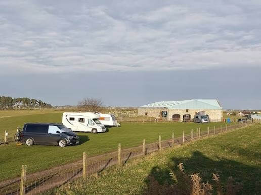Wohnmobil und Wohnwagen auf den Wiesenparzellen der Davochfin Farm.